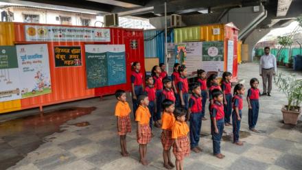 Des élèves chantent l'hymne national indien à "l'école du feu rouge" qui accueille des enfants défavorisés dans des conteneurs aménagés en salles de cours sous un pont autoroutier, le 18 mai 2026 à Bombay