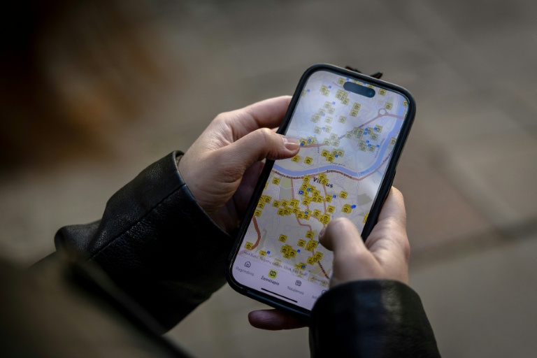 Ruta Gaskauskaite présente sur son téléphone une application qui permet aux utilisateurs de trouver les abris les plus proches, à Vilnius, le 28 mai 2026, en Lituanie