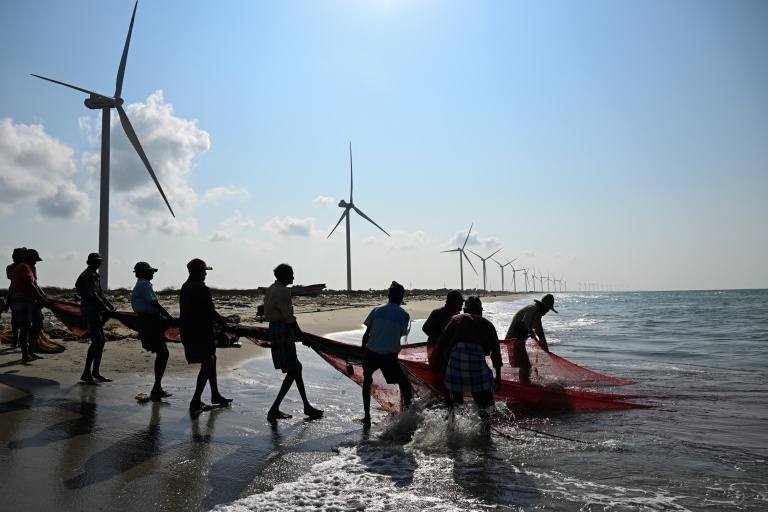 Cette photo, prise le 3 octobre 2026, montre des pêcheurs en train de pêcher sur une plage située près d'un parc éolien, sur la péninsule de Mannar, au Sri Lanka
