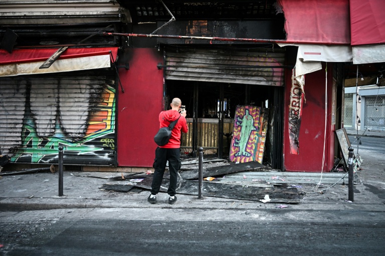 Un passant prend en photo la façade du restaurant 