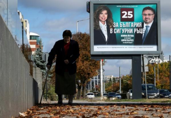Une personne marche devant une affiche électorale de la présidente sortante de Bulgarie, Iliana Iotova, et de son vice-président candidat Kiril Valchev, à Sofia, le 23 octobre 2026