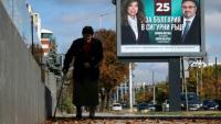 Une personne marche devant une affiche électorale de la présidente sortante de Bulgarie, Iliana Iotova, et de son vice-président candidat Kiril Valchev, à Sofia, le 23 octobre 2026