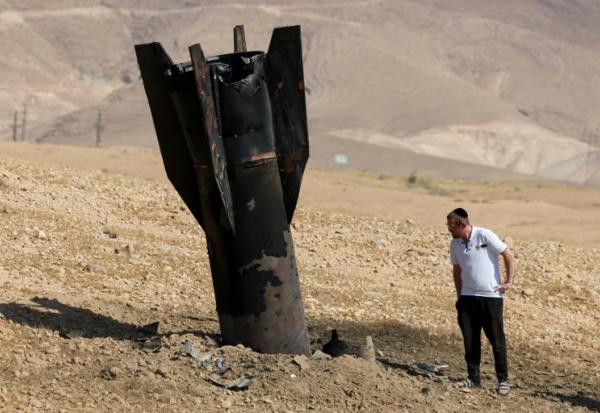 Un Israélien inspecte un missile tombé, à moitié enfoui dans le sol, en périphérie de Jéricho en Cisjordanie, le 8 juin 2026