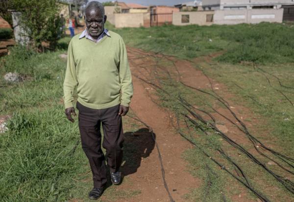 Un habitant du township de Katlehong, près de Johannesburg, marche à côté des câbles qui raccordent illégalement son quartier au réseau électrique, le 5 octobre 2026