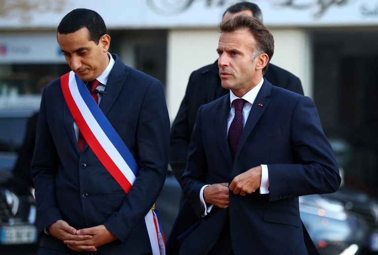 Le président français Emmanuel Macron (D) marche aux côtés du maire de Trappes, Ali Rabeh, à son arrivée pour une réunion à l'hôtel de ville après une fusillade survenue à Trappes, le 23 octobre 2026